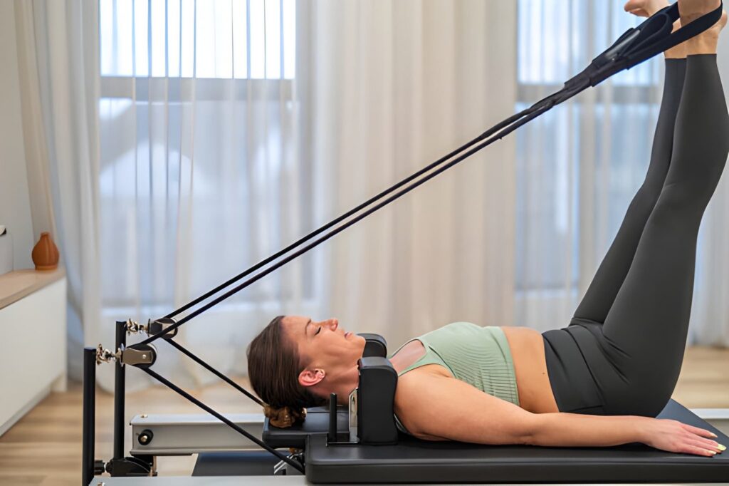 Woman performing Pilates reformer exercise with straps