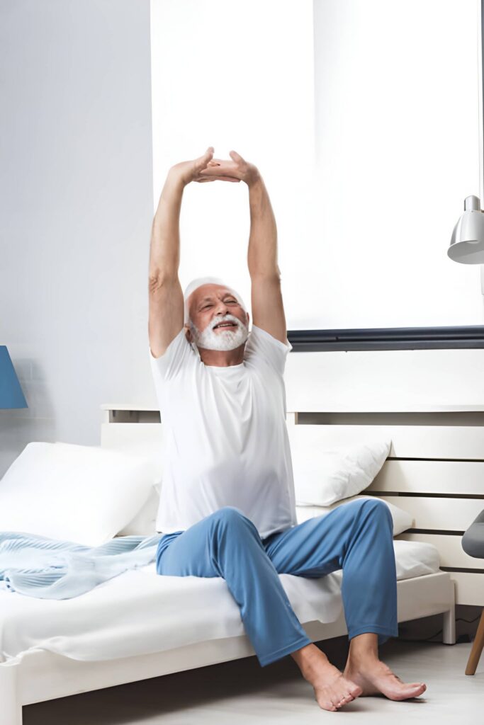 Senior man stretching on bed in bedroom