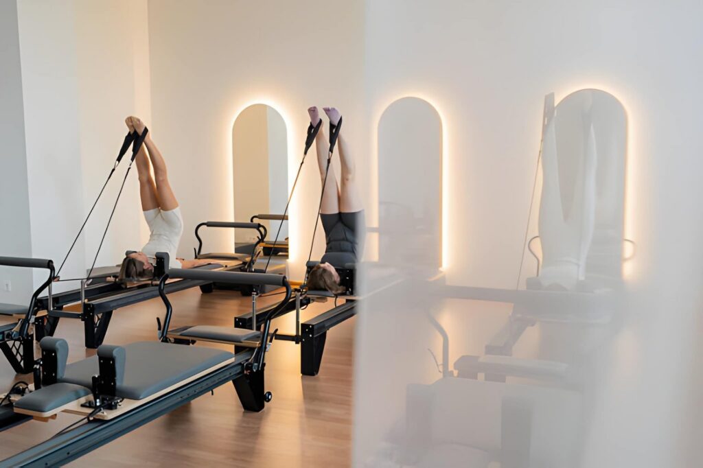 Two women doing reformer Pilates, legs raised