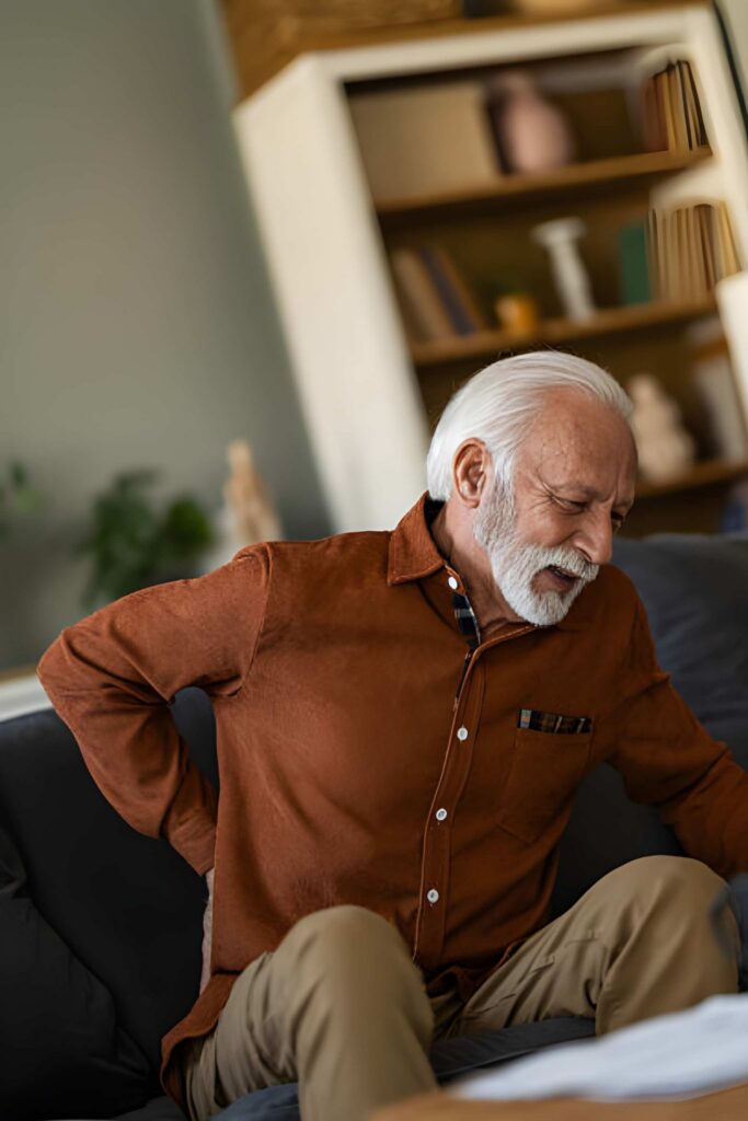 Elderly man with back pain sitting on couch