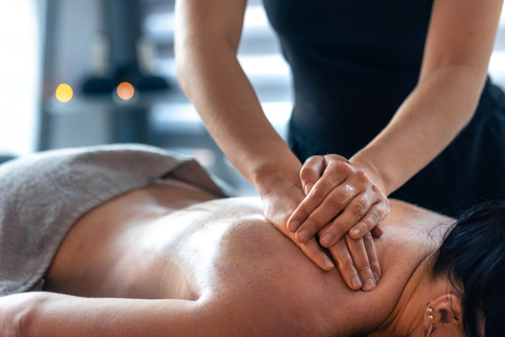 Massage therapist giving shoulder massage to client